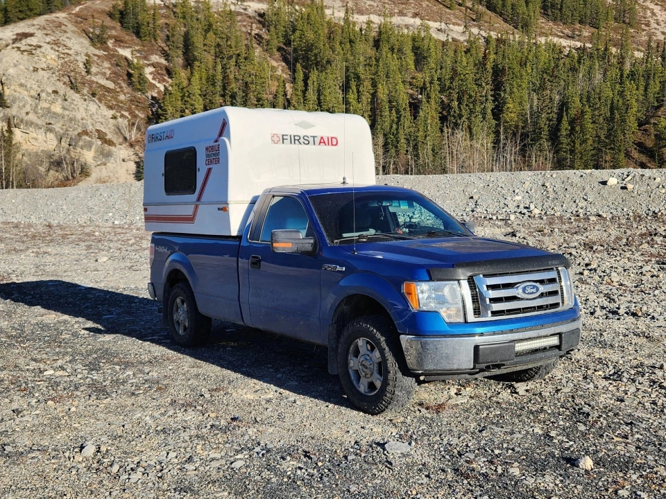 A blue truck with a camper on the back.