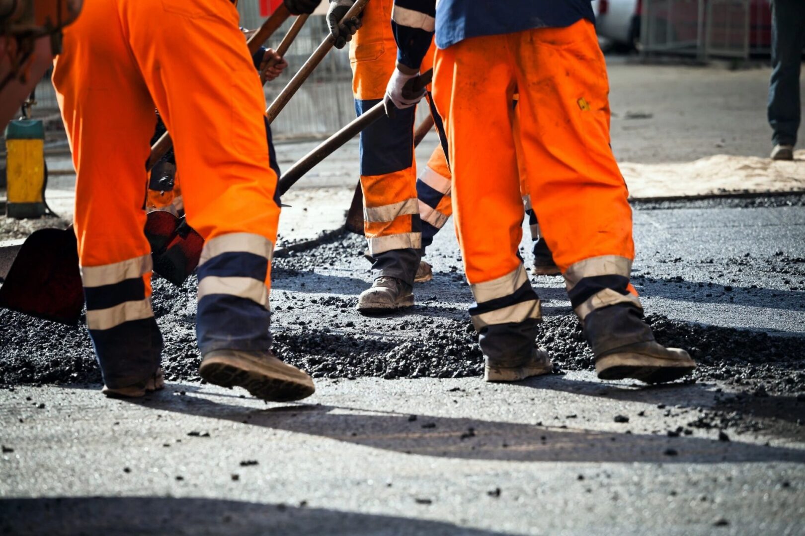 A group of workers in orange pants and safety gear.
