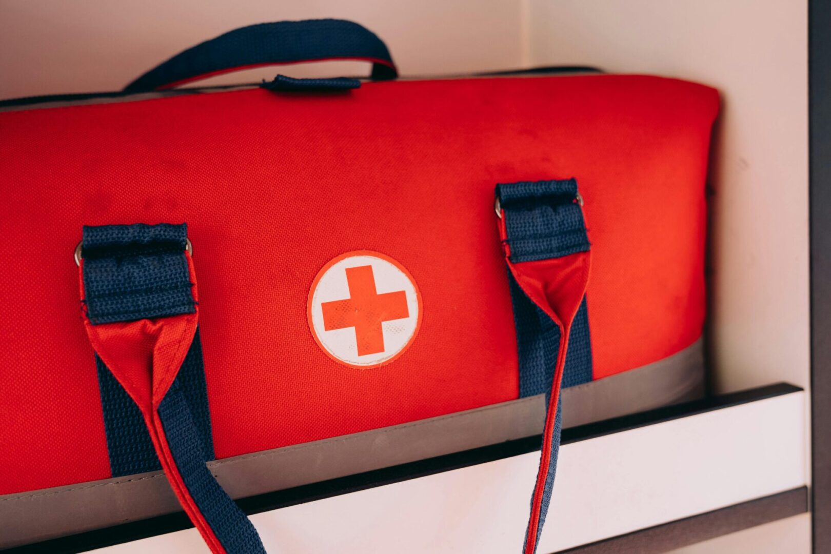 A red and white first aid kit sitting on top of a table.